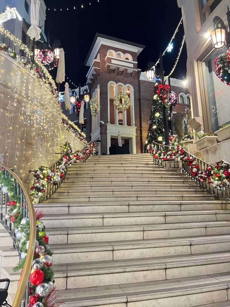 An outdoor staircase wrapped in garland and ornaments