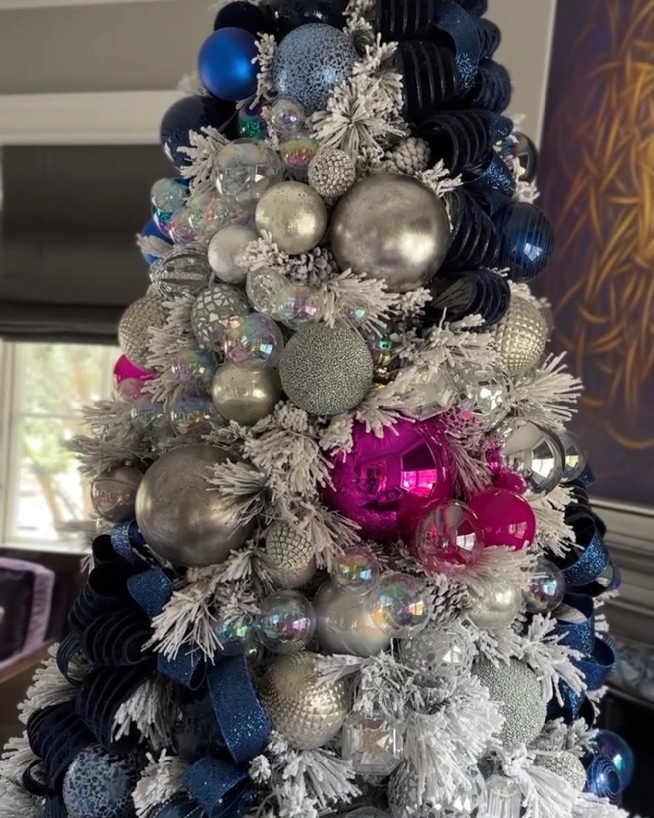 A flocked tree dressed in navy, silver and pink ornaments