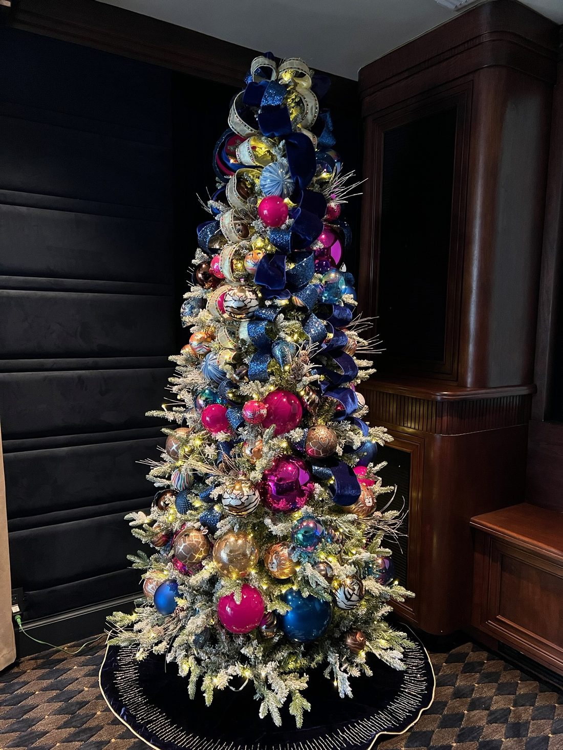 A flocked tree with pink, gold and blue ornaments
