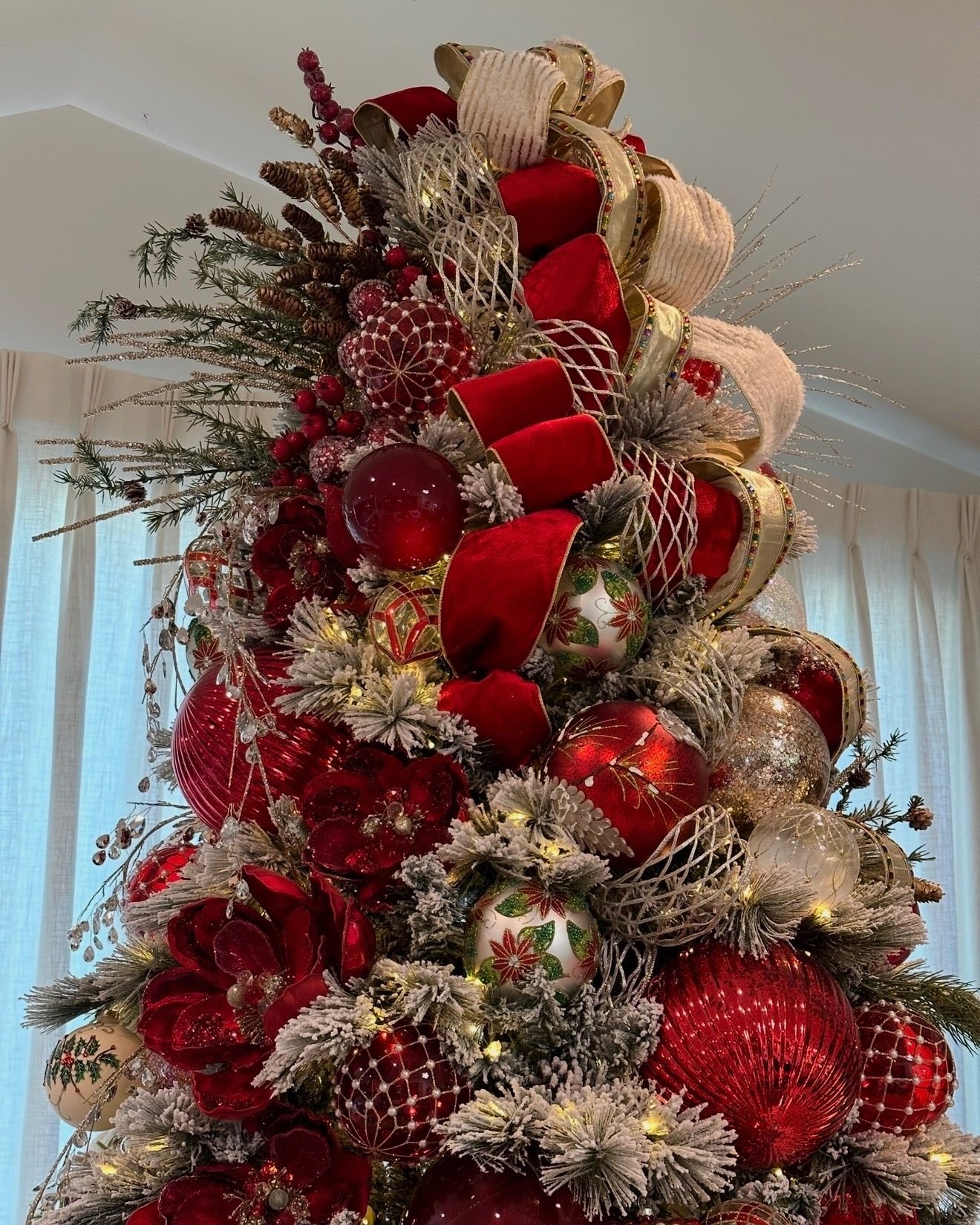 A flocked tree layered with red velvet ribbon, magnolias and red and gold ornaments