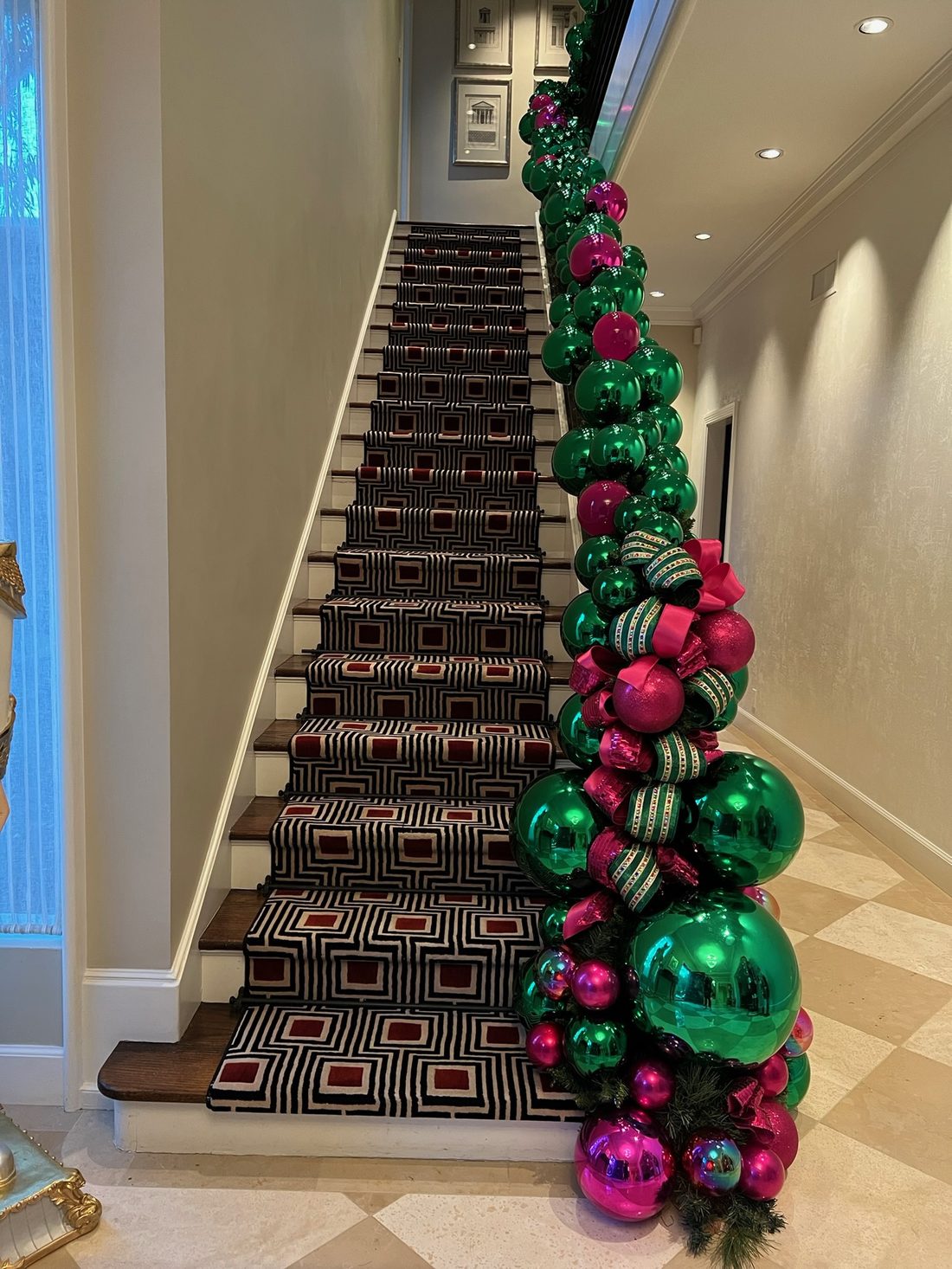A staircase wrapped in jewel toned ornament garland